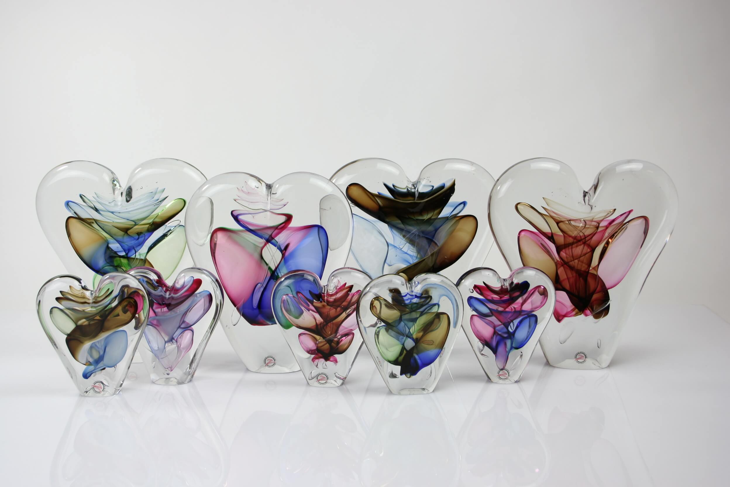 Row of heart shaped glass sculptures with colourful blown glass detail inside clear crystal